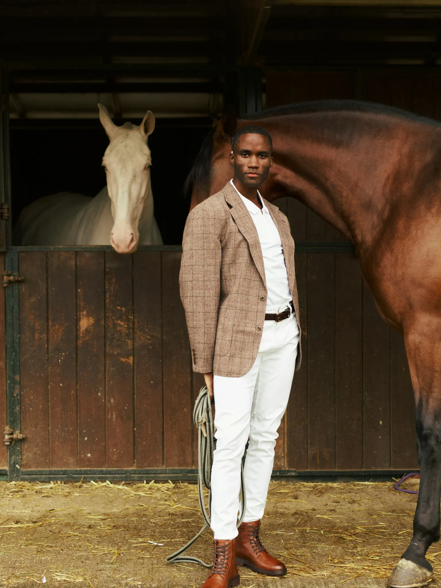 A man standing beside horses at a stable