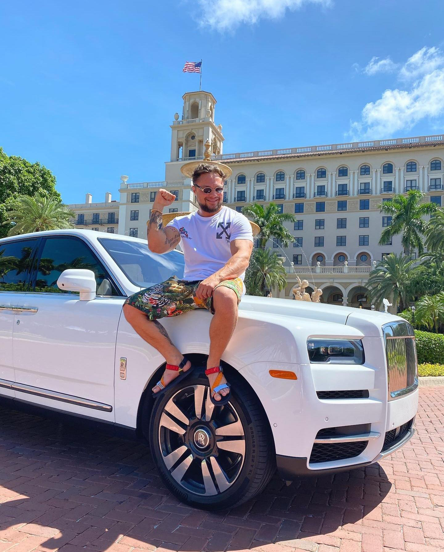 A guest beside a Rolls-Royce at a resort entrance.